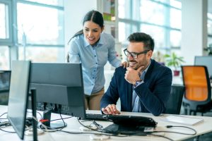 Male boss discussing online project with employee in the office